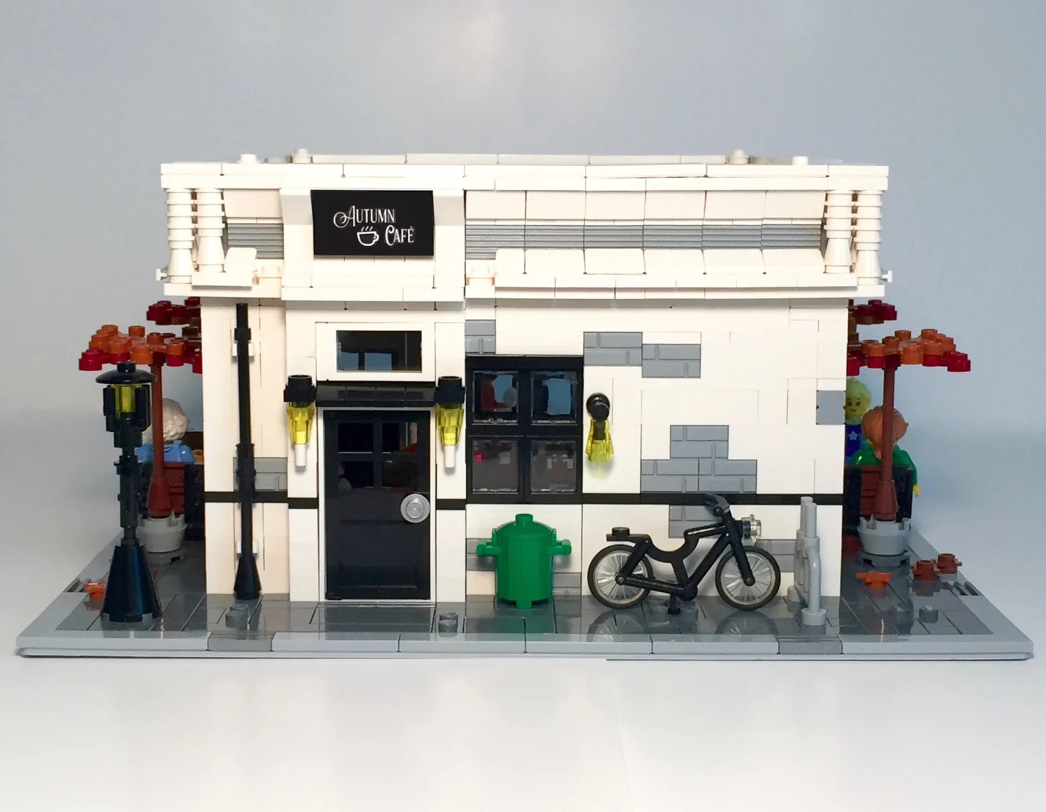 Back exterior of the physical Autumn Café LEGO model with outdoor tables, lattice railing and autumn trees