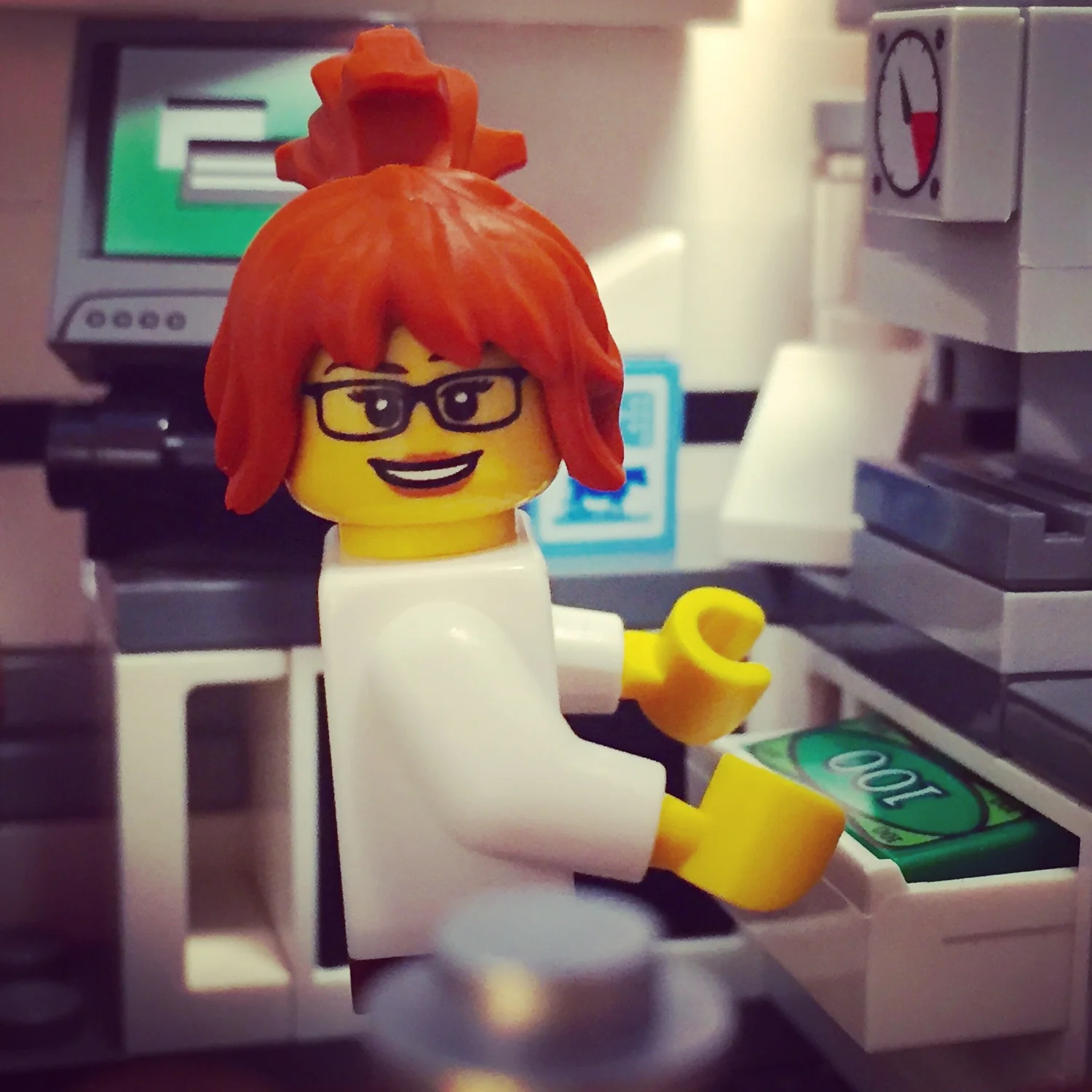 Close-up of the female barista minifigure with red hair and glasses at the cash drawer