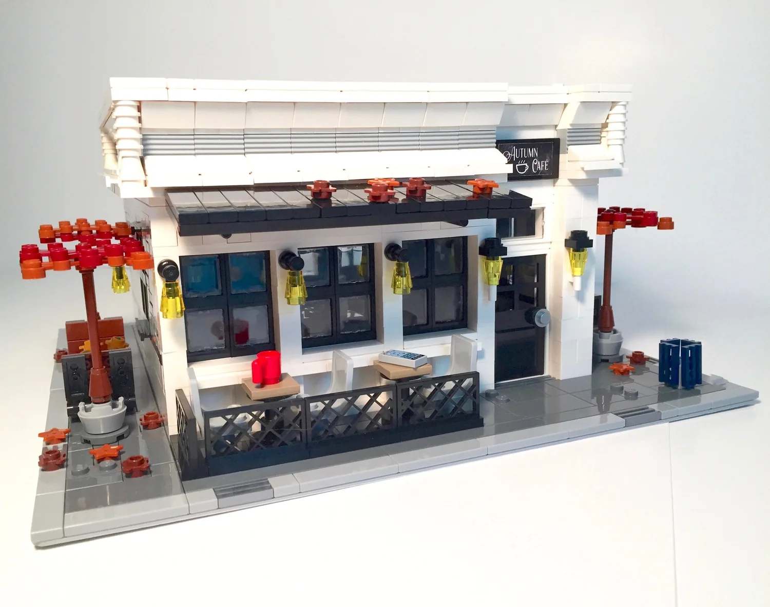 Front exterior of the physical Autumn Café LEGO model with a bicycle and green trash can