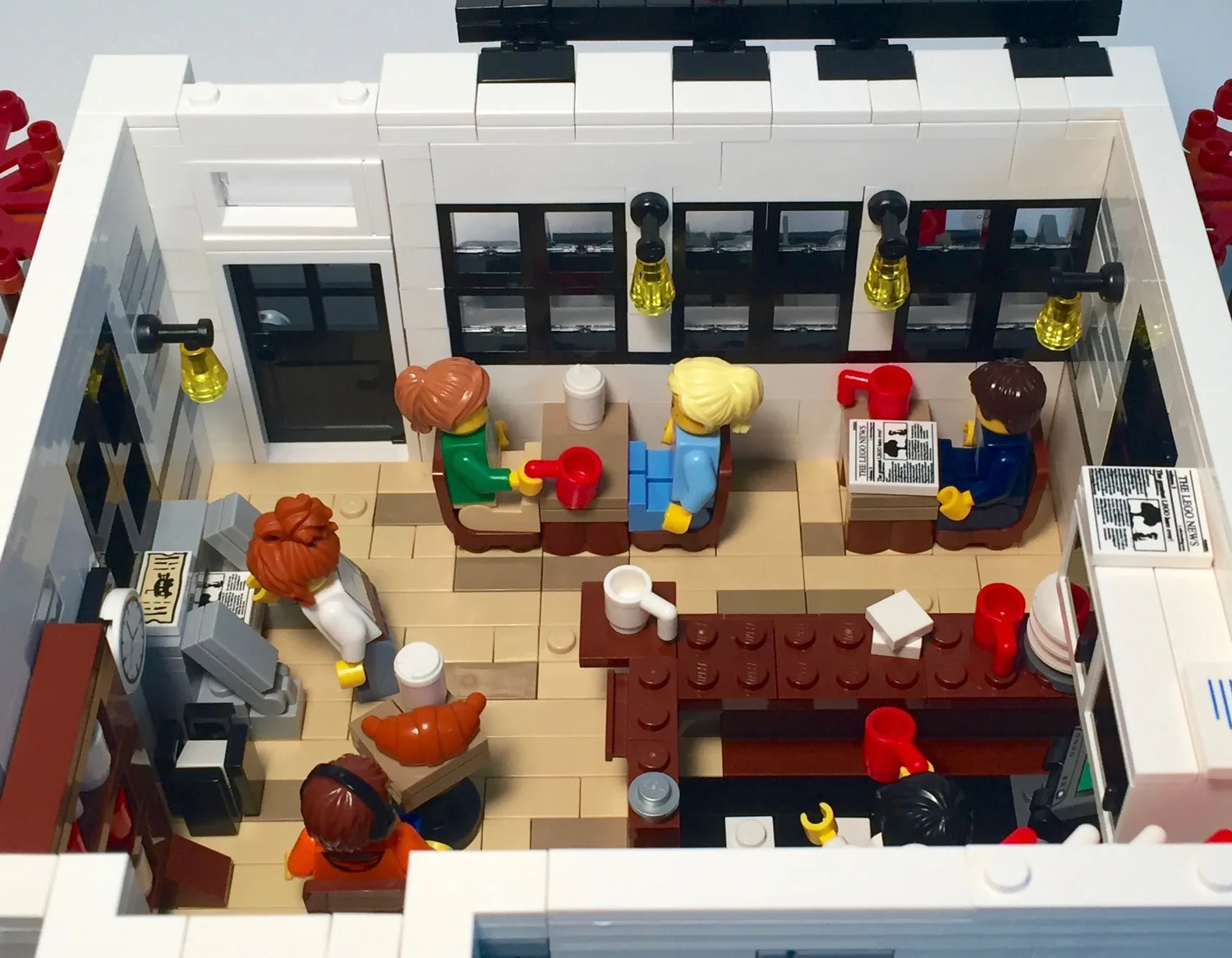 Interior of the Autumn Café LEGO model showing the service area, dining tables and minifigure patrons