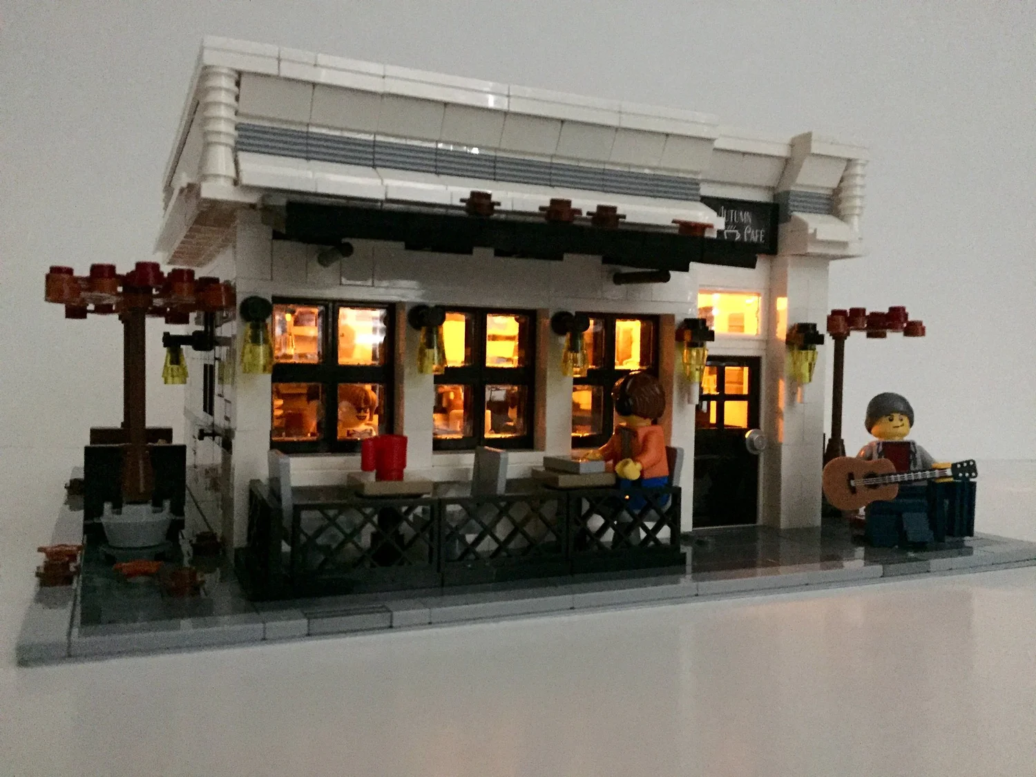The Autumn Café LEGO model at night with warm light glowing from the windows