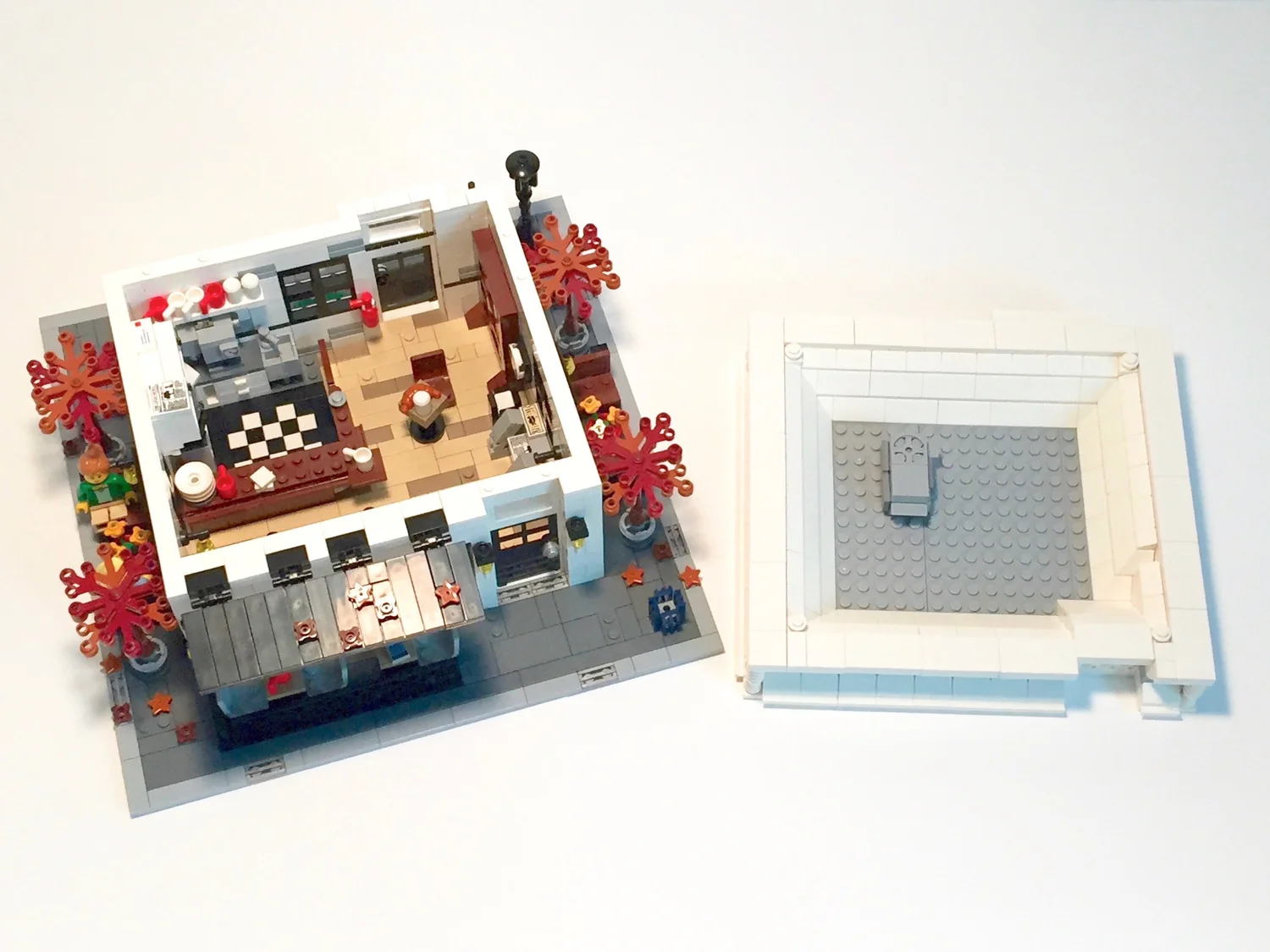 Top-down view of the Autumn Café LEGO model with the roof lifted off beside it