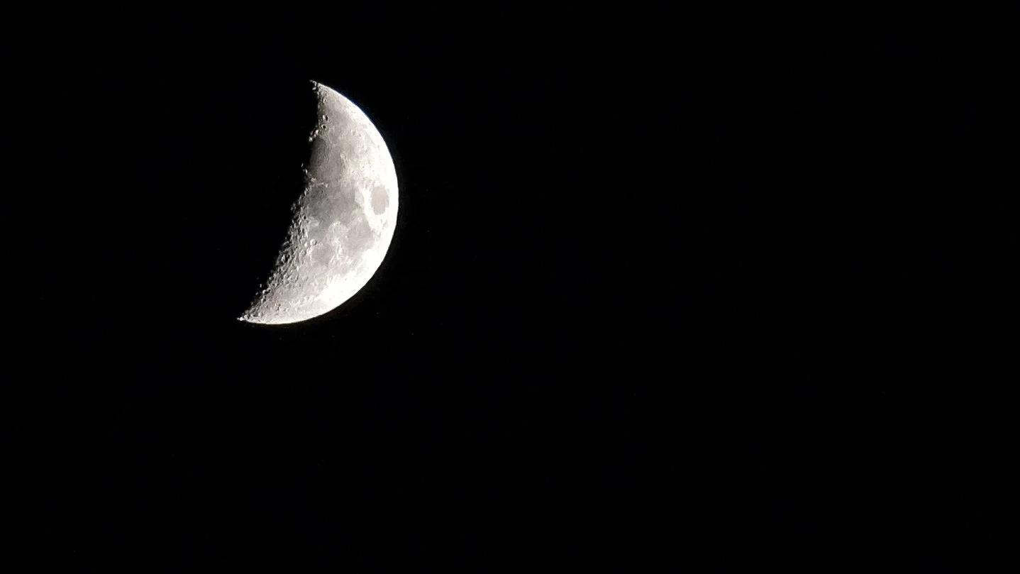 Crescent moon with visible craters against a black sky