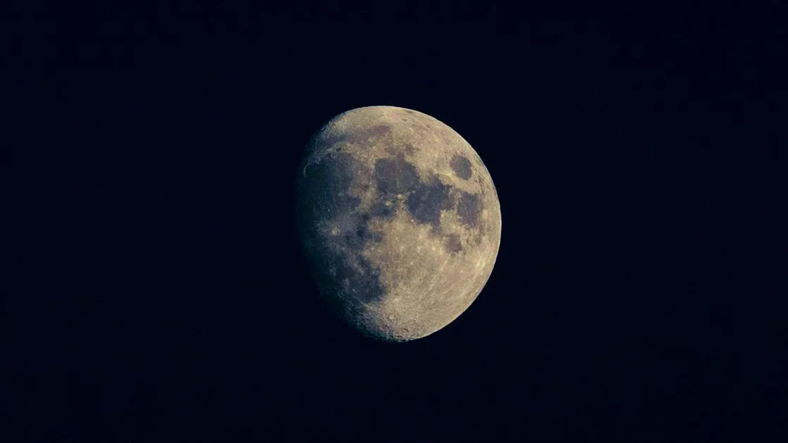 Nearly full moon with golden tones against a dark blue sky