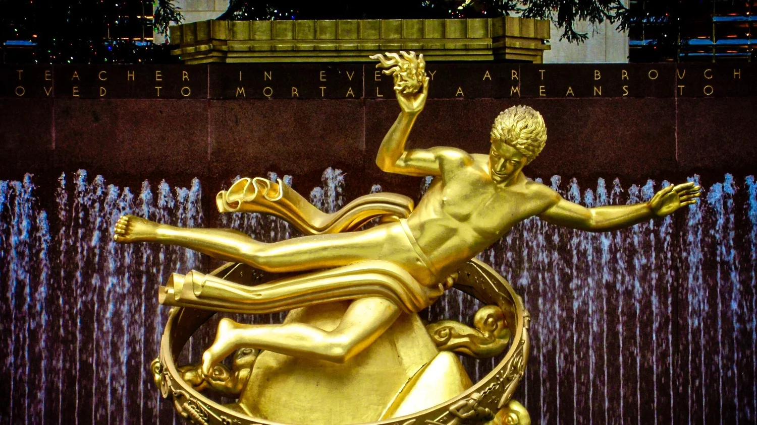 Gilded statue of a flying figure in front of a wall of falling water