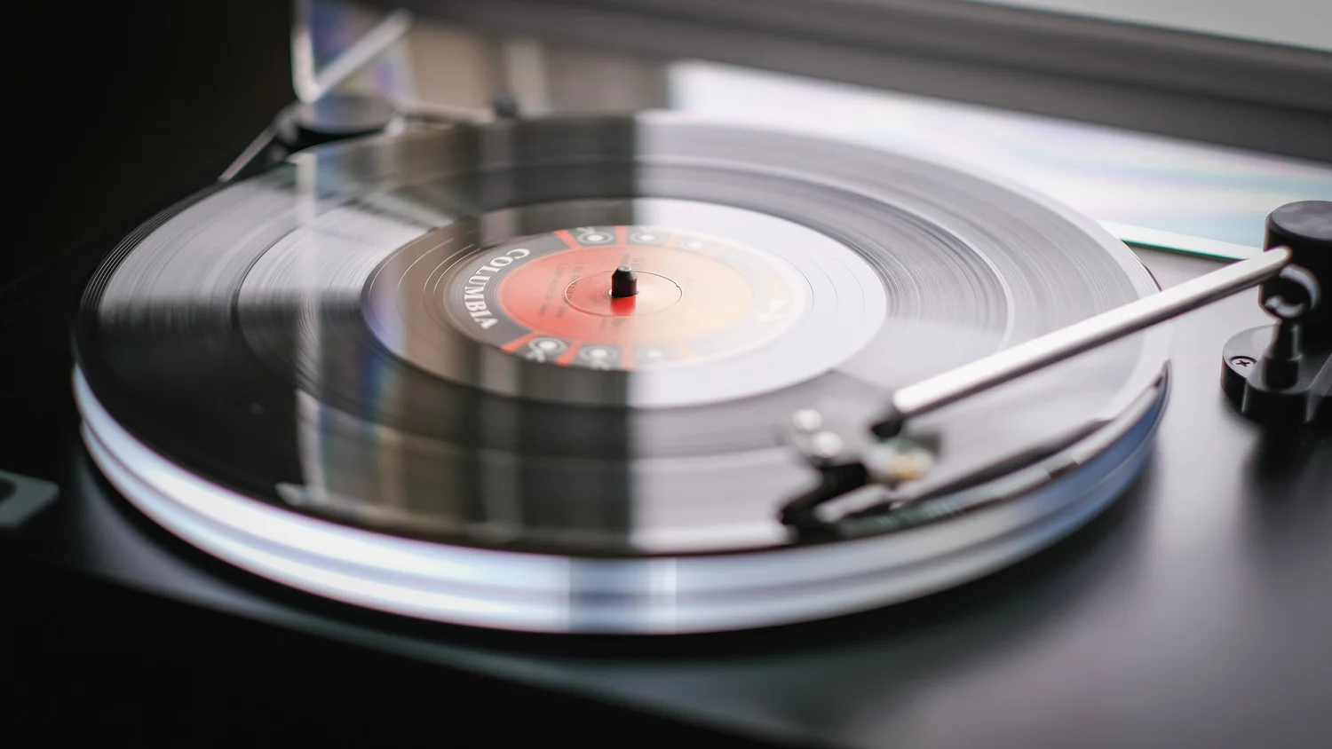 Vinyl record spinning on a turntable with the tonearm resting on it